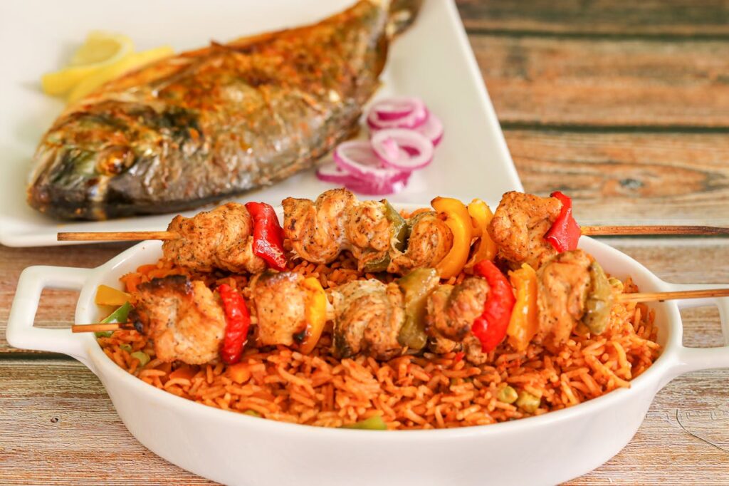 pexels-photo-13915043 Close-up of flavorful Nigerian jollof rice with grilled chicken skewers and roasted fish.